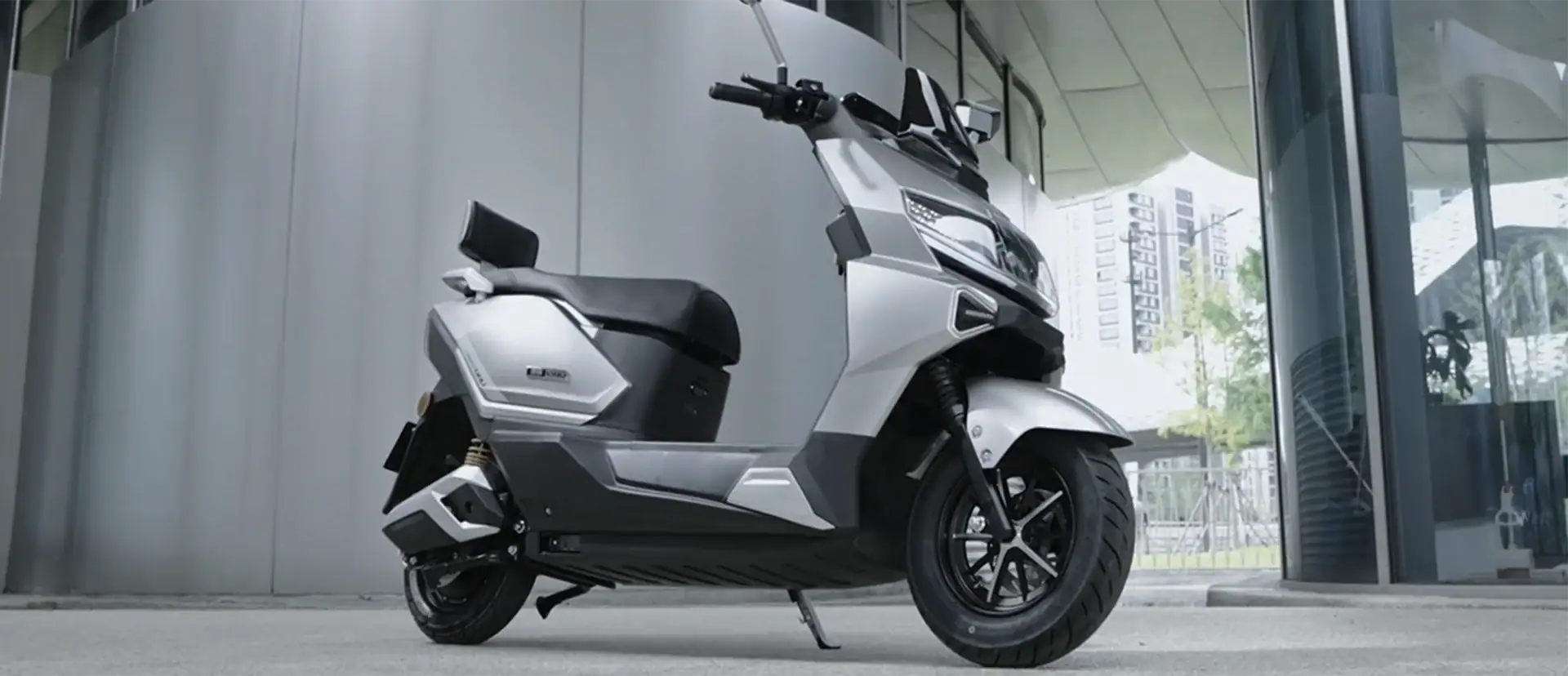 产品/场景电动滑板车 parked outside a modern building, showcasing innovative transportation technology suitable for city commuting.