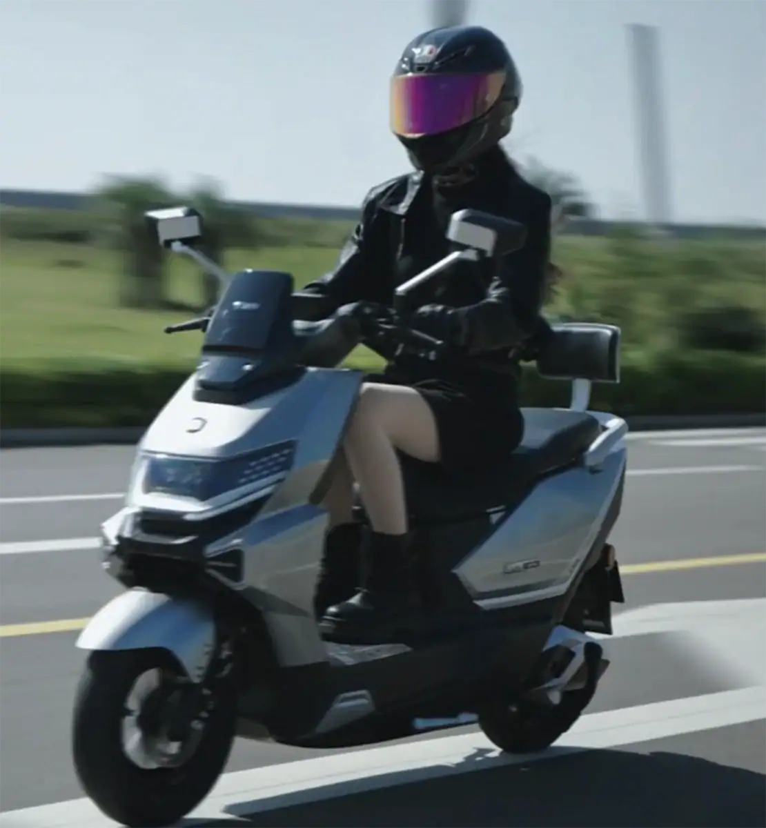 产品/场景电动滑板车 wearing a black helmet and black gear, driving fast on the street, showcasing modern personal transportation technology.