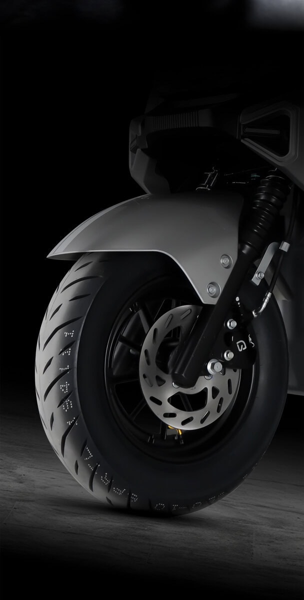 Close-up of a modern electric scooter front wheel showcasing sleek design and disc brake system, ideal for eco-friendly urban transportation.